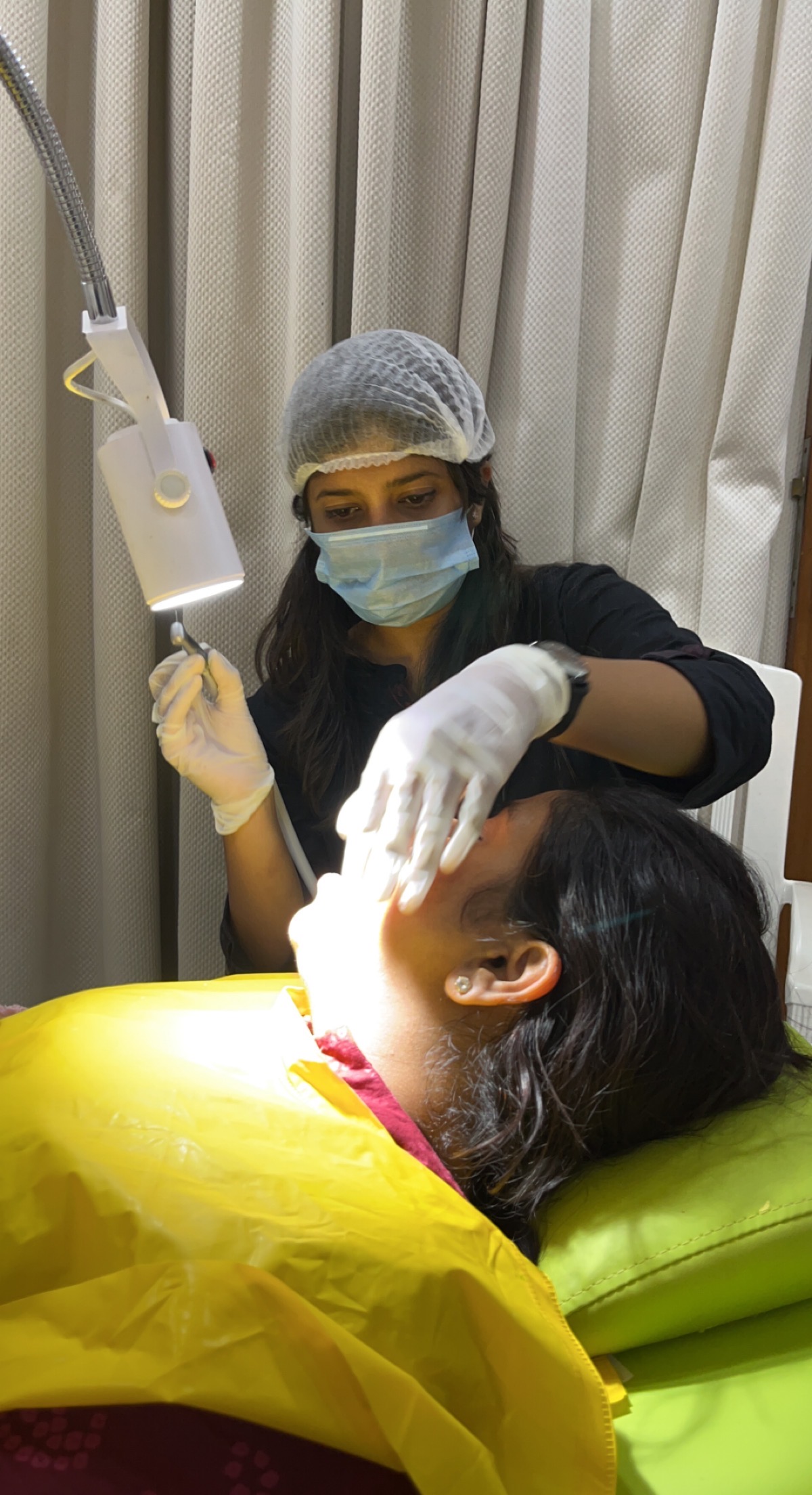 Prudentoe dentist using a portable dental lamp during a home dental treatment in Hyderabad
